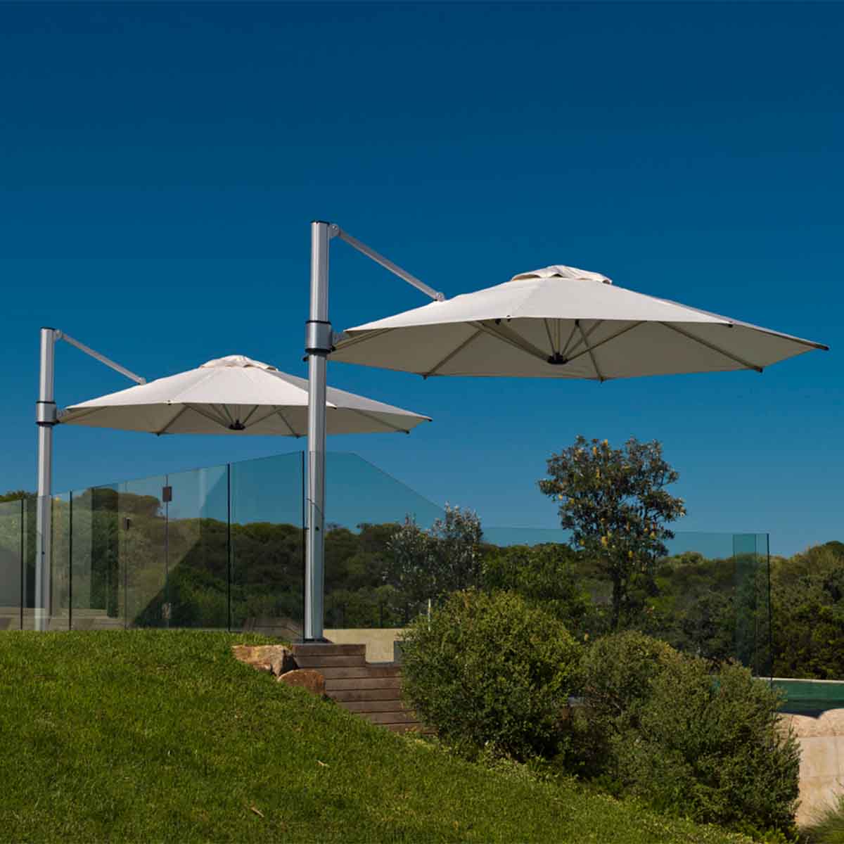 two commercial cantilever outdoor umbrellas over a swimming pool