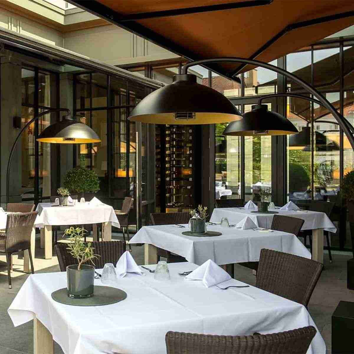 three commercial outdoor freestanding heaters at an outdoor seating area of a hospitality venue
